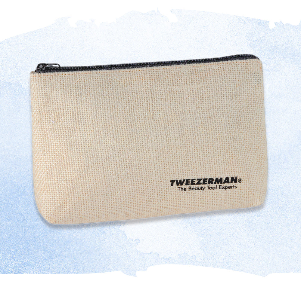 A beige woven cosmetic pouch with a black zipper and black printed Tweezerman logo, shown on a light blue watercolor-style background.
