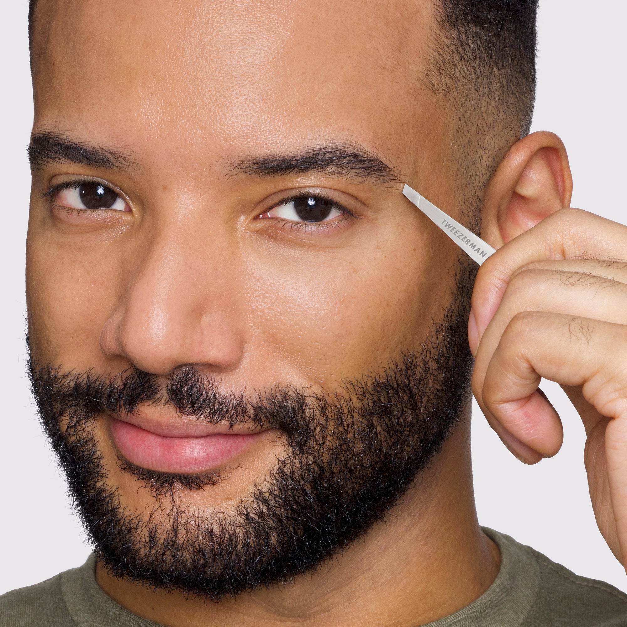 Modèle masculin utilisant une pince à épiler classique en forme de mini inclinaison sur les sourcils