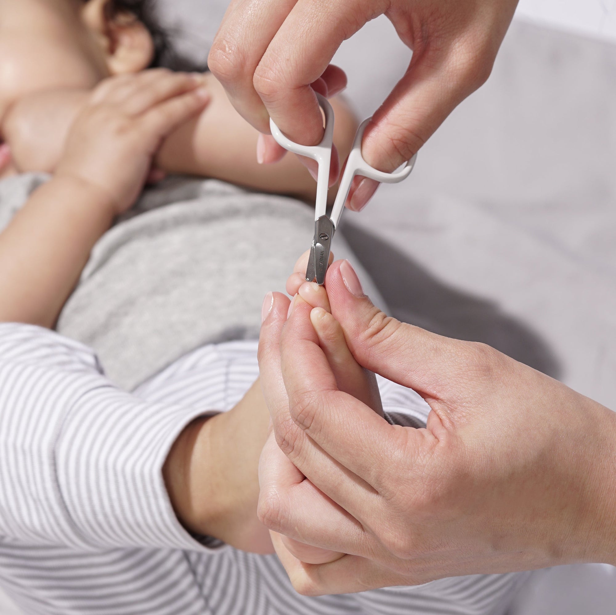 Model using Green Baby nail scissors on baby's feet