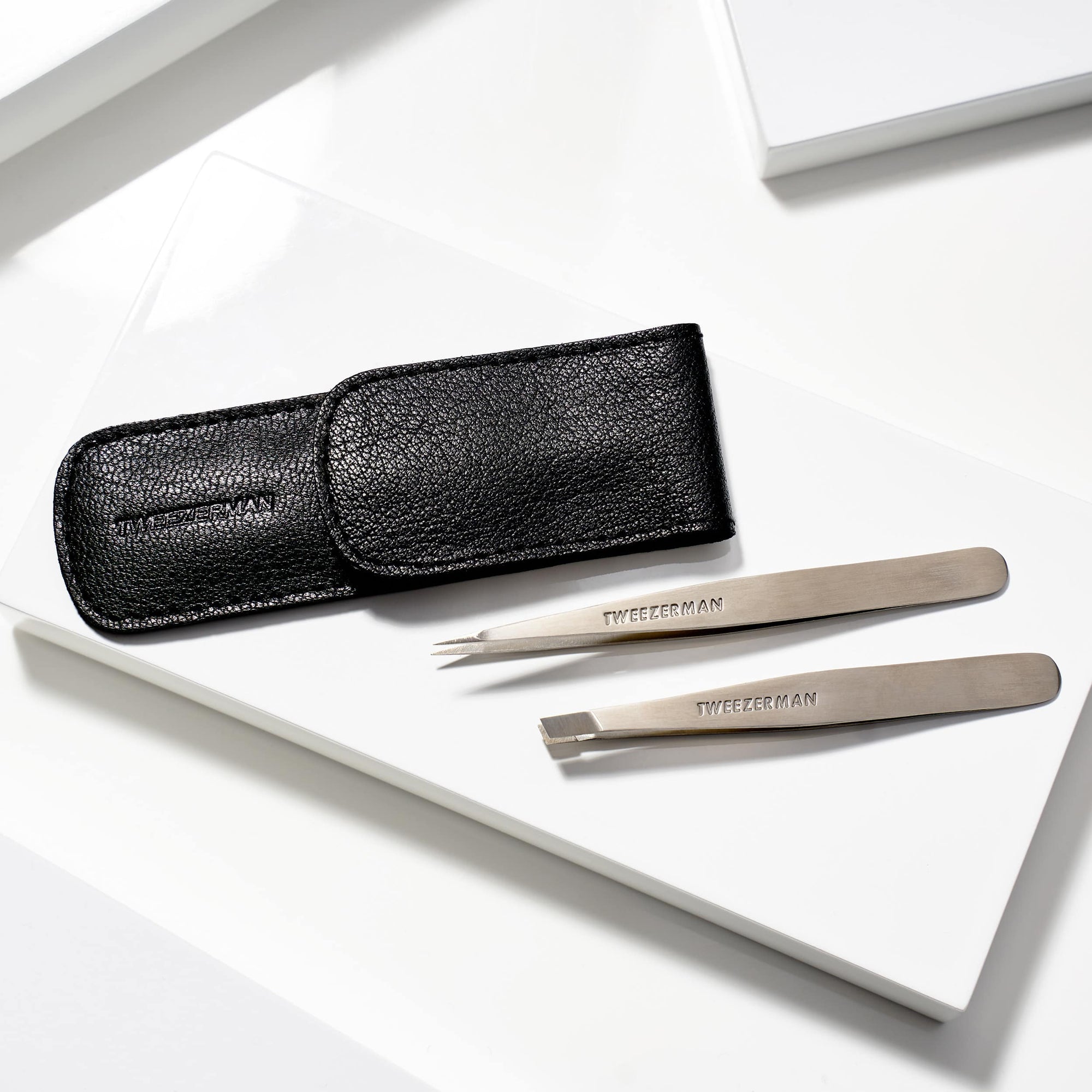 Set of tweezers with a black leather case on a white surface