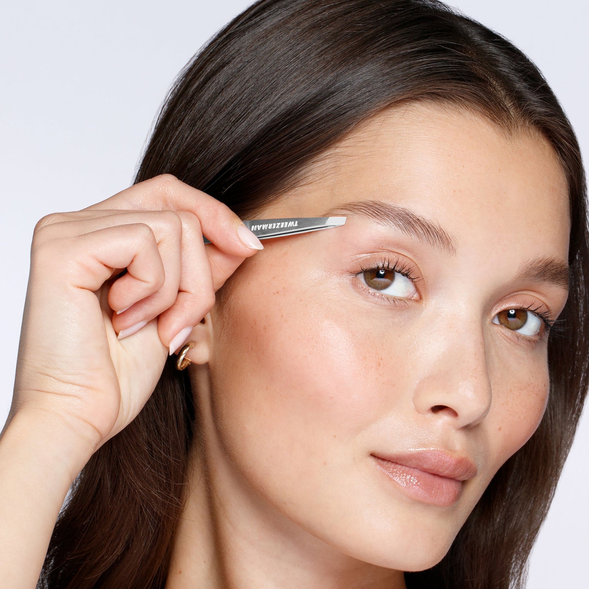 Mannequin féminine utilisant une pince à épiler mini inclinée classique sur les sourcils
