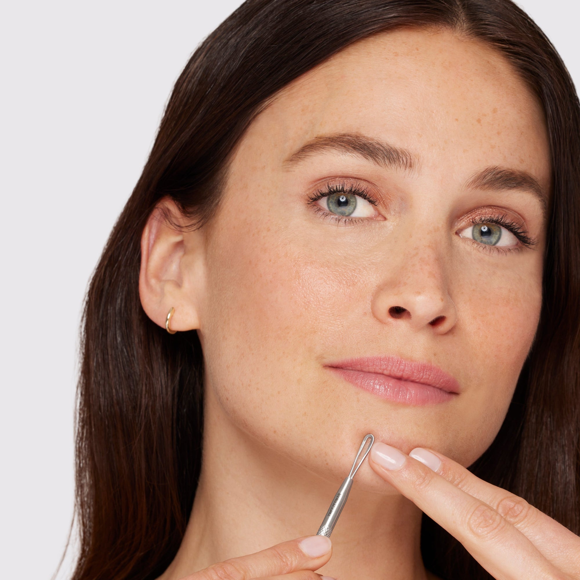 Mannequin féminine utilisant une longue boucle plate à l’extrémité de l’outil de soins de la peau